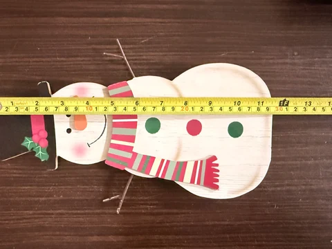 Quality inspection using a tape measure on a finished snowman decoration at Keren Crafts